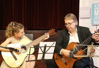 Uczennica podczas nauki gry na gitarze z instruktorem