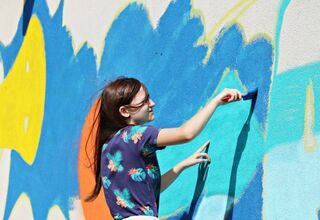 Dziewczyna maluje mural na ścianie