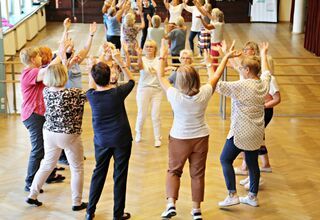 Kobiety stojące w kole z rękoma uniesionymi do góry