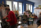 Trzy kobiety siedzą przy sztalugach i malują obrazy