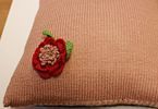 Fragment poduszki z ozdobnym kwiatem ręcznie haftowanym