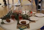 Stół ozdobiony gałązkami choinek. Na stole stoi dzbanek i szklanki z herbatą oraz talerzyki z piernikami.