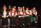 Zespół złożony z kobiet i mężczyzn, śpiewający kolędy na scenie