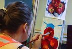 Uczestniczka warsztatów podczas tworzenia swojego obrazu malowanego akrylem