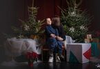 Matka z synem pozująca do zdjęcia na świątecznym tle w formie choinek z lampkami, prezentów, siedząca na świątecznym fotelu i pufach DK Zacisze