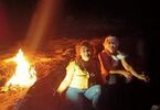 Dwie kobiety siedzą w ciemności, z boku płonie ogień