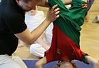 Dziecko stojące na głowie na macie przy asyście instruktora