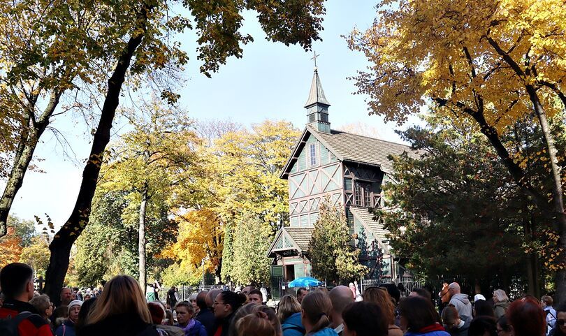 Zielony drewniany kościół i grupa ludzi