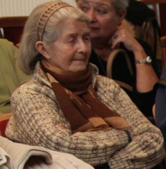 Starsza kobieta siedzi z zamkniętymi oczami