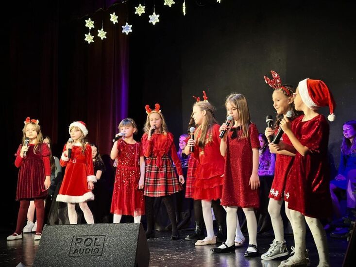 Dziewczynki w czerwonych strojach śpiewają na scenie
