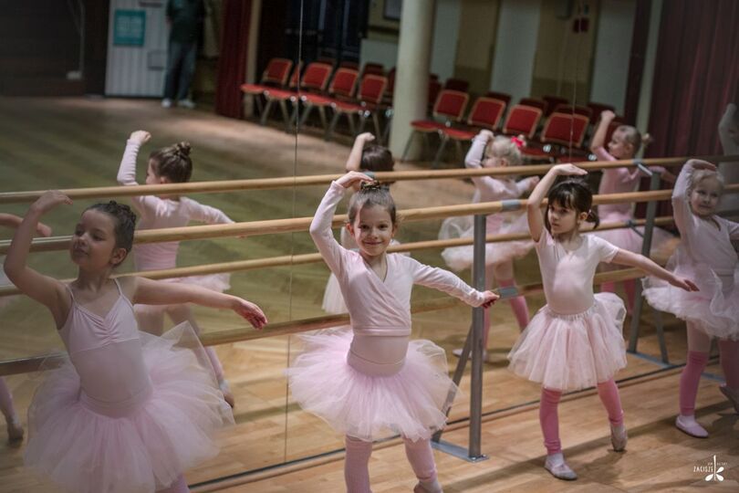 Dziewczynki w różowych spódnicach w pozie tanecznej, z  tyłu lustra