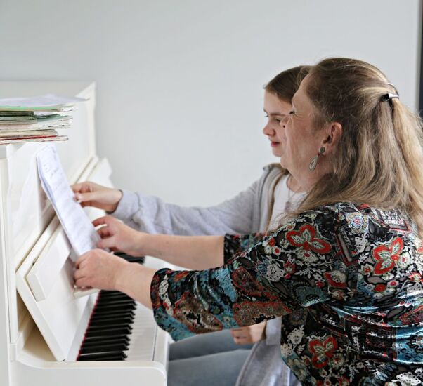 Nastolatka i kobieta z długimi włosami podczas gry na pianinie